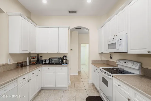 a kitchen with granite countertop white cabinets and white appliances