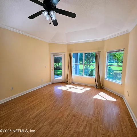 an empty room with wooden floor fan and windows