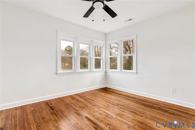 a view of an empty room with wooden floor and window