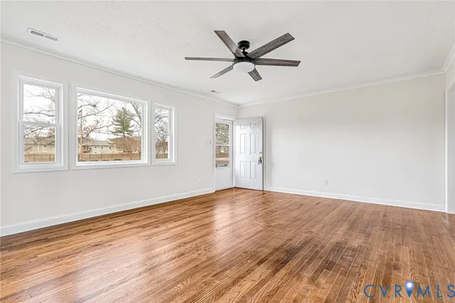 a view of empty room with wooden floor and fan