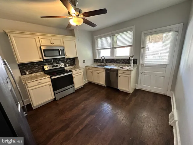 a kitchen with granite countertop a stove top oven a sink and dishwasher a refrigerator with wooden floor