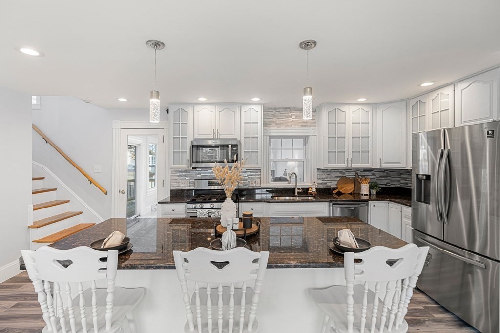 60 Florence Street Lowell, MA 01852 - Photo 11 of 42 a kitchen with stainless steel appliances kitchen island granite countertop a refrigerator a stove top oven and white cabinets