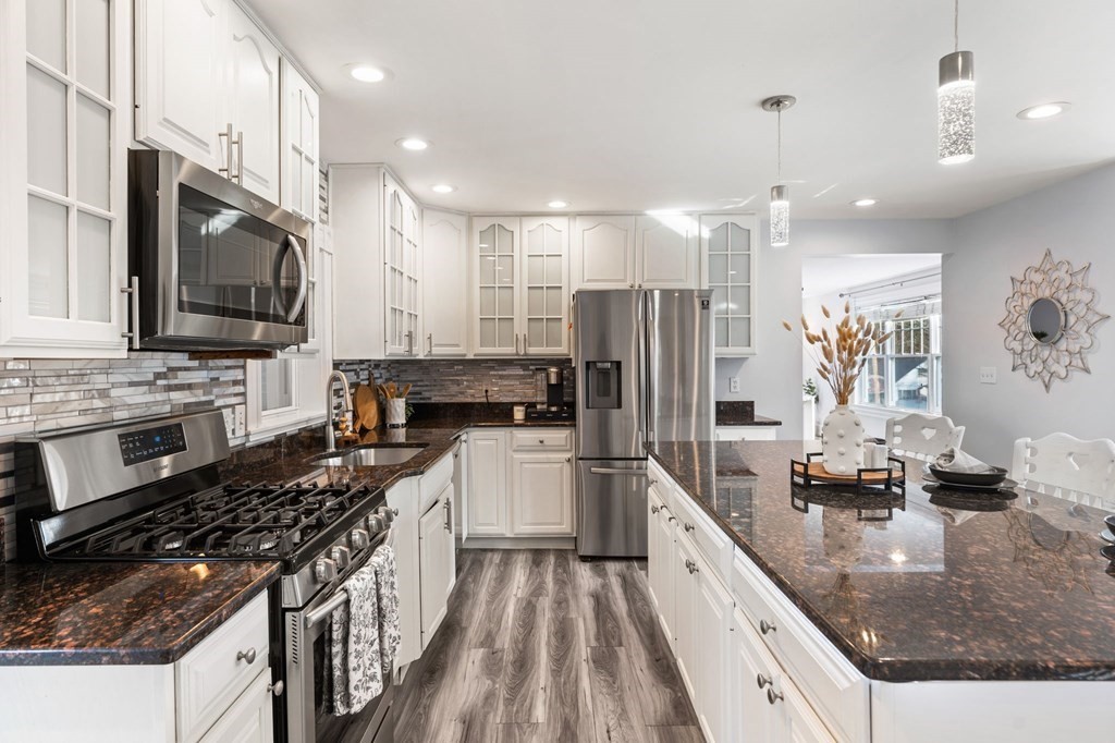 60 Florence Street Lowell, MA 01852 - Photo 9 of 42 a kitchen with stainless steel appliances granite countertop a stove top oven a sink dishwasher a refrigerator and a dining table with wooden floor