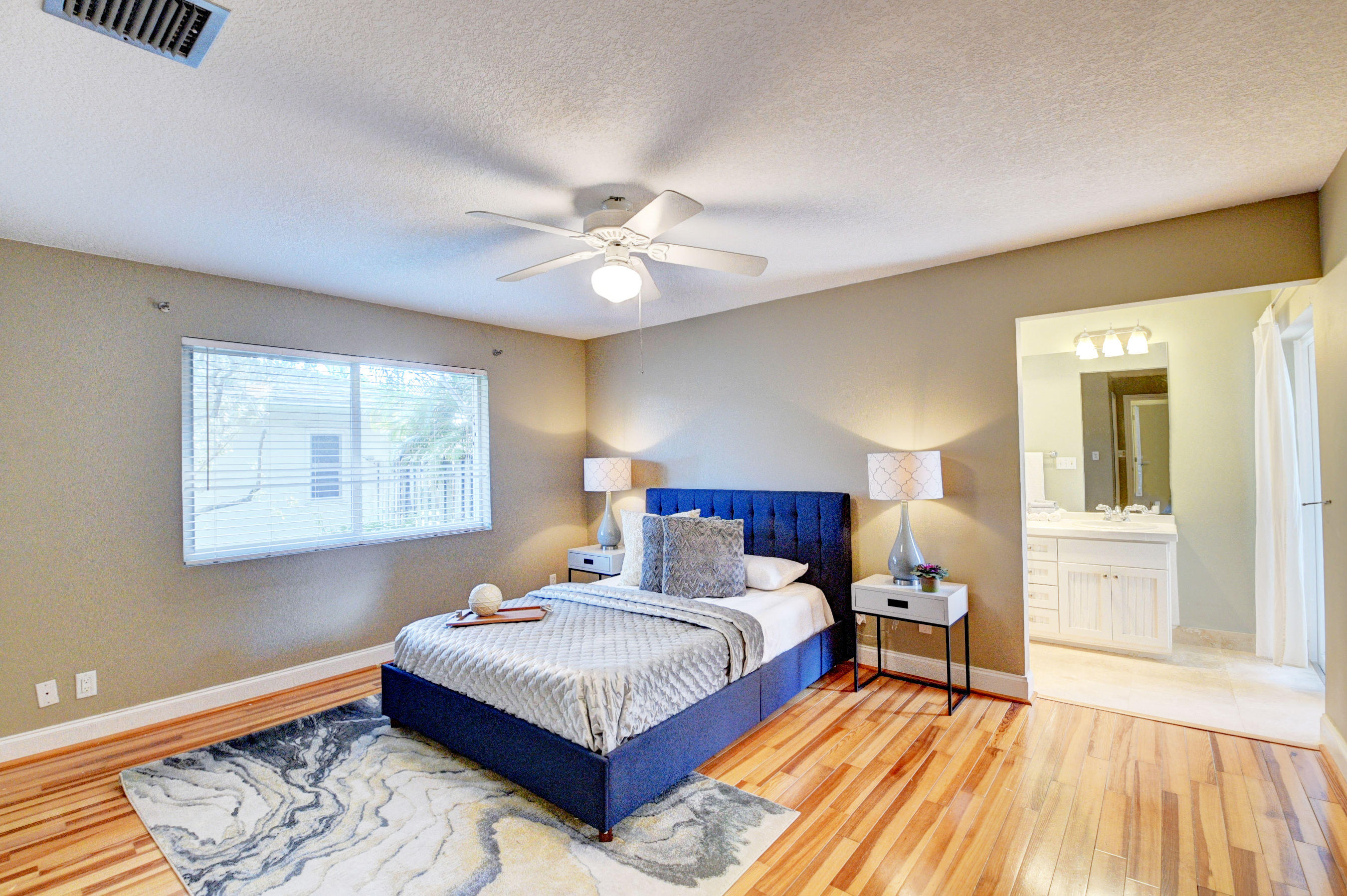 1990 Bonnie Street Boca Raton, FL 33486 - Photo 17 of 28 a spacious bedroom with a bed and wooden floor