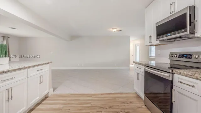 a kitchen with white cabinets and window