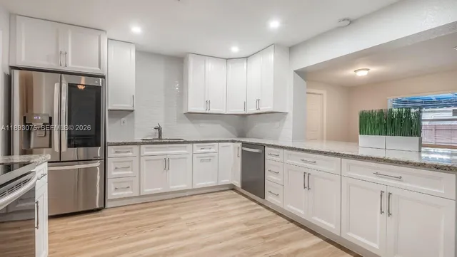 a kitchen with granite countertop white cabinets and white appliances