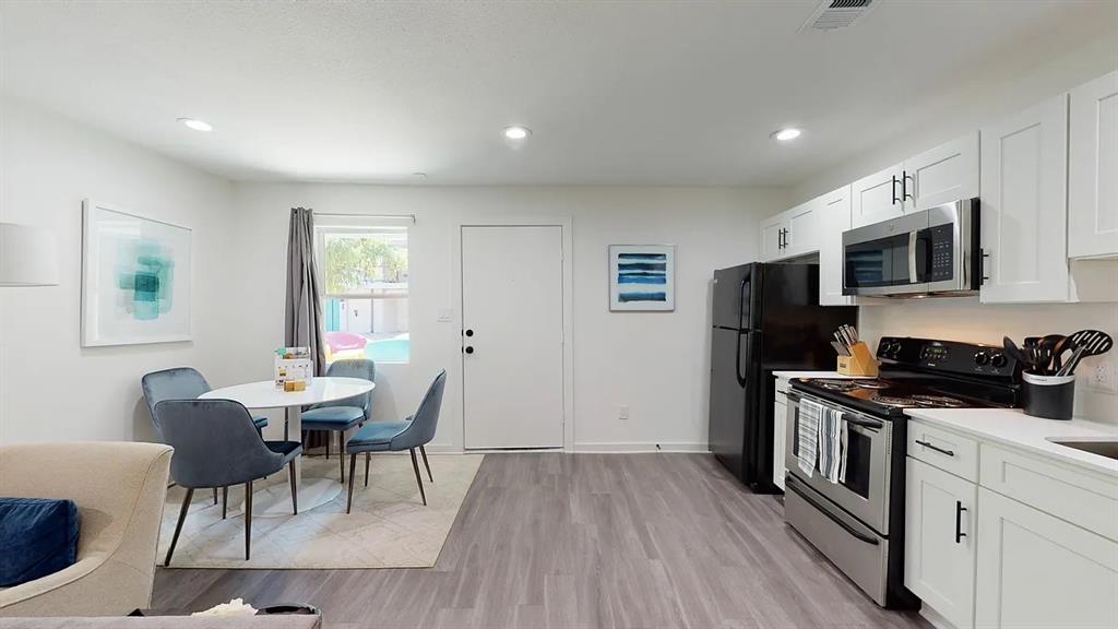 321 East 8th Street, Unit 104 Dallas, TX 75203 - Photo 2 of 15 a kitchen with stainless steel appliances a stove a sink a refrigerator white cabinets and wooden floor