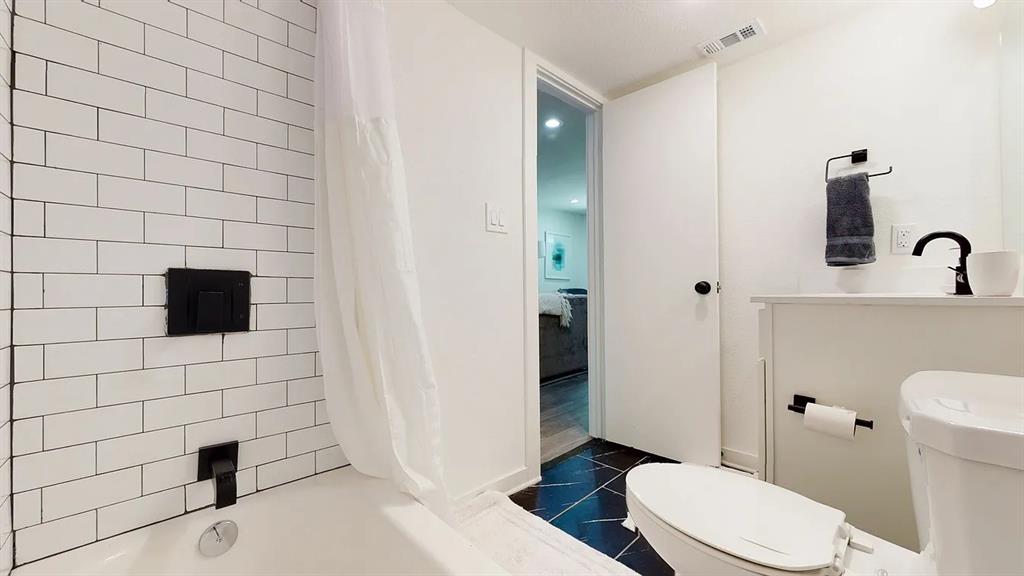 321 East 8th Street, Unit 104 Dallas, TX 75203 - Photo 6 of 15 a bathroom with a toilet a sink and a mirror