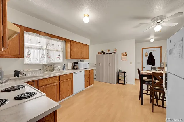 a white kitchen with stainless steel appliances a refrigerator a table and chairs