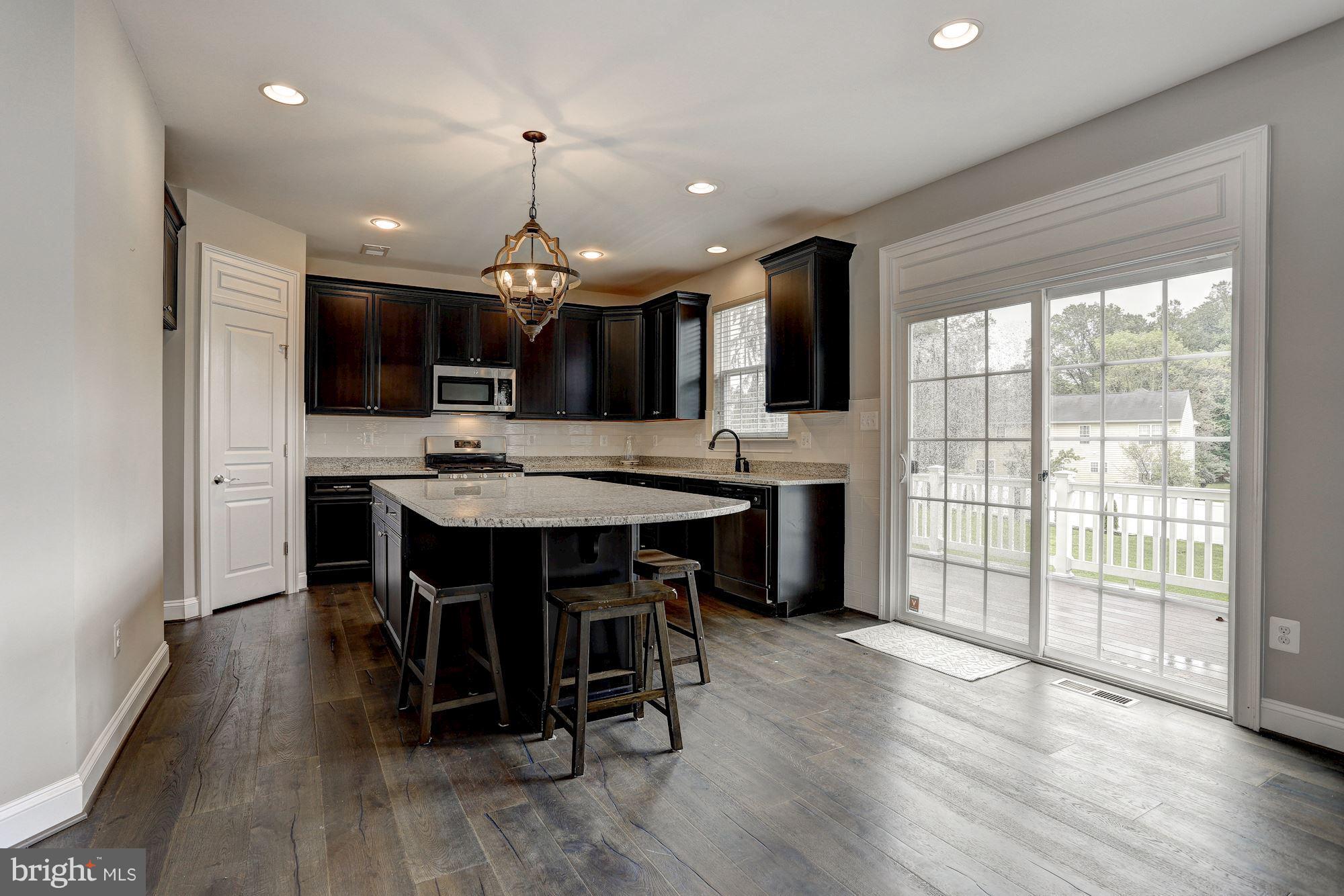 8420 High Ridge Road Ellicott City, MD 21043 - Photo 8 of 30 a kitchen with stainless steel appliances kitchen island granite countertop a table chairs sink and cabinets