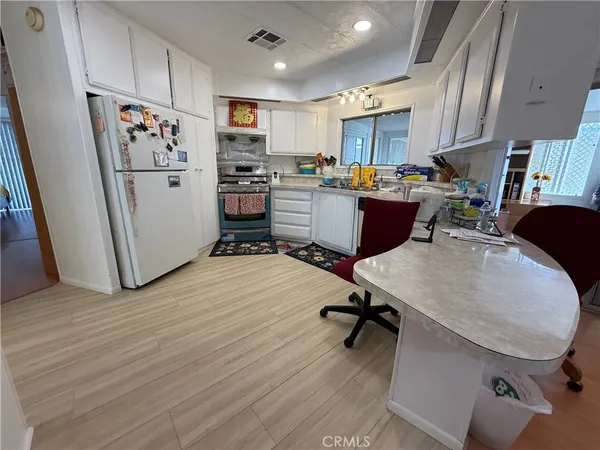 a living room with stainless steel appliances furniture a refrigerator and a dining table with wooden floor
