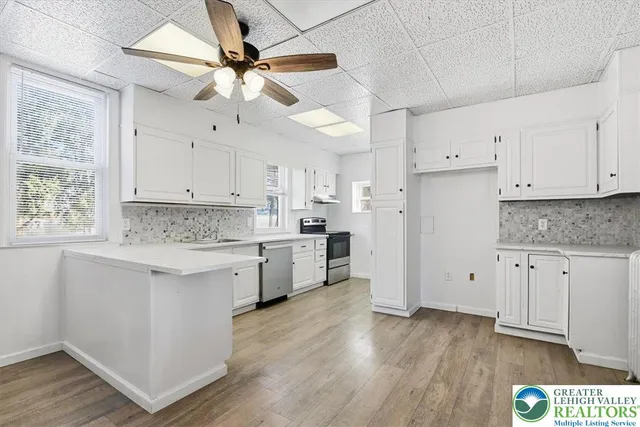 a kitchen with granite countertop a sink cabinets stainless steel appliances and a window