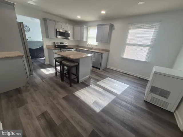 a kitchen with stainless steel appliances granite countertop a refrigerator a stove a sink dishwasher and microwave with wooden floor