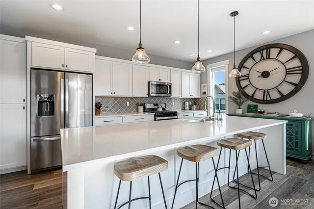 a kitchen with stainless steel appliances granite countertop a refrigerator a stove a sink dishwasher a dining table and chairs with wooden floor