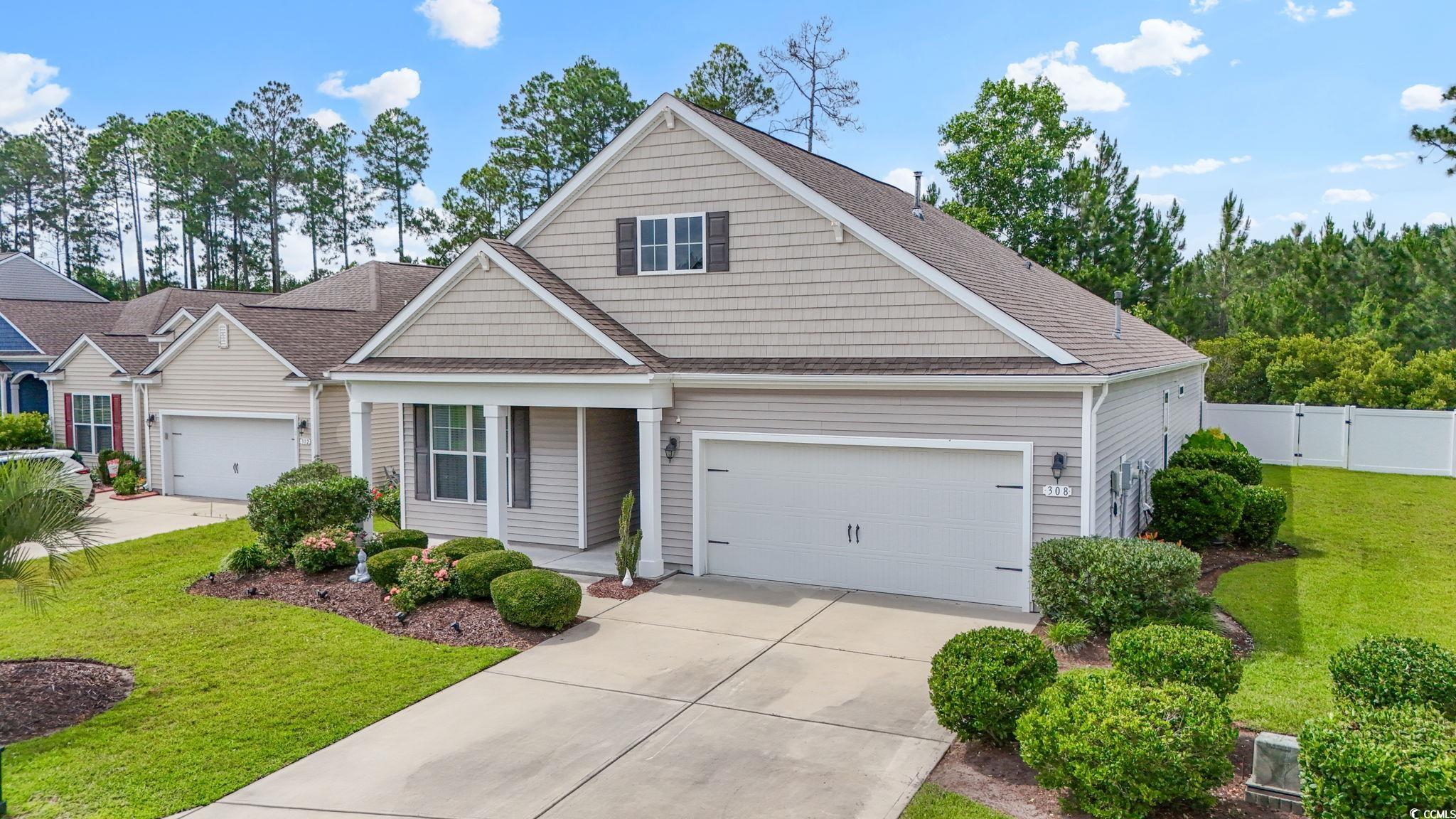 Traditional home featuring concrete driveway, a garage, a shingled roof, and a gate