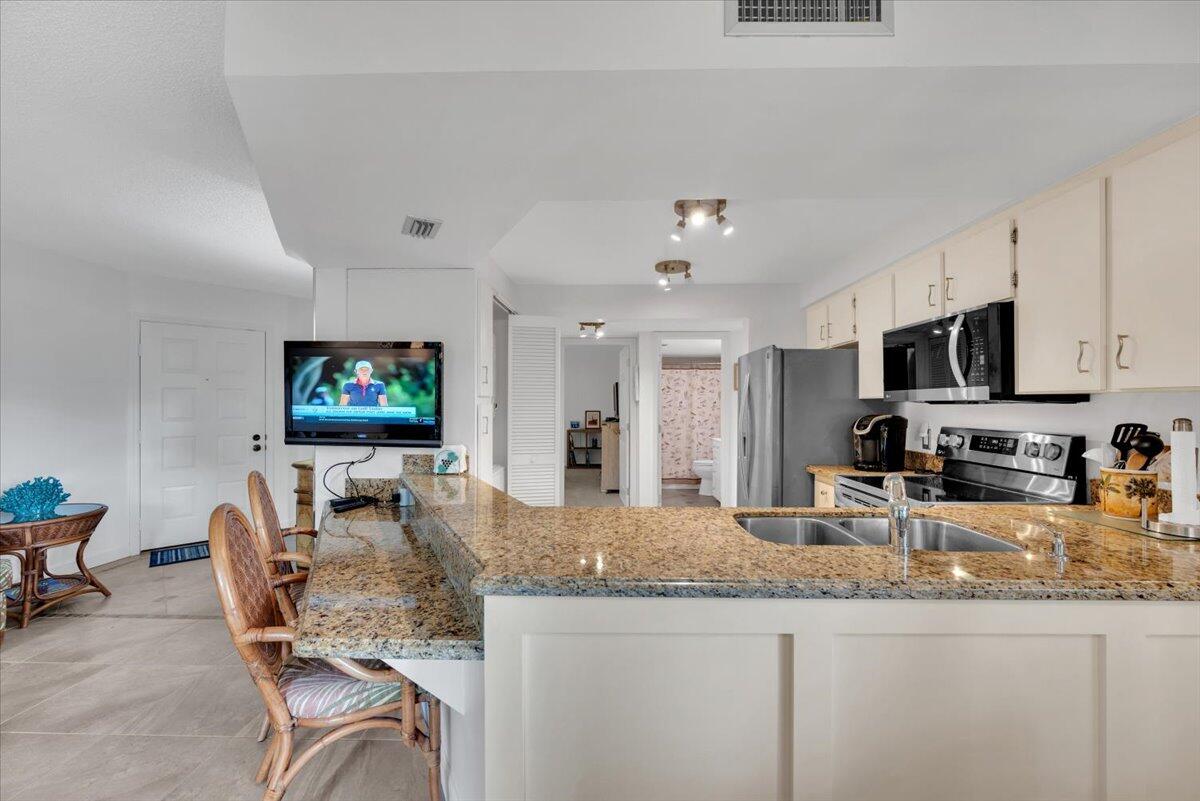 1605 Highway 1, Unit E201 Jupiter, FL 33477 - Photo 13 of 19 a kitchen with stainless steel appliances granite countertop a sink and a microwave