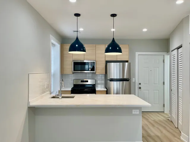 a kitchen with stainless steel appliances a stove a refrigerator a sink a center island and couches