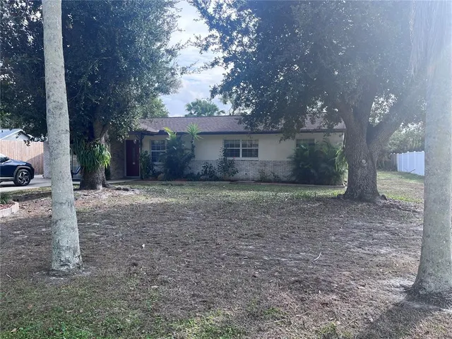 a view of a house with a yard and large tree