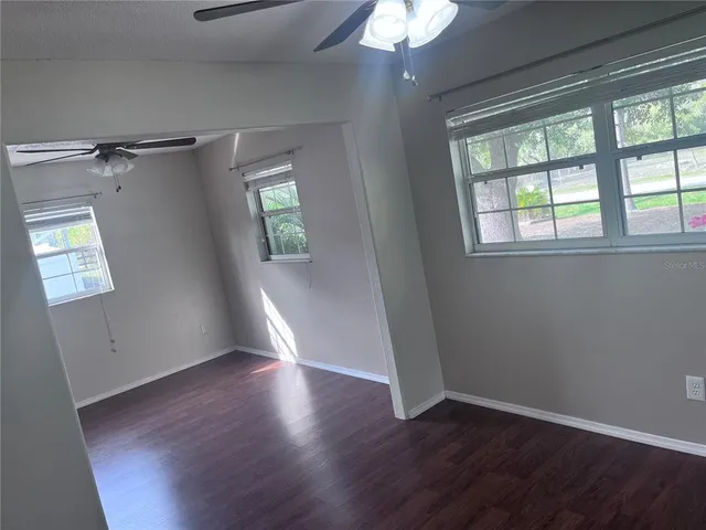 a view of empty room with wooden floor and fan