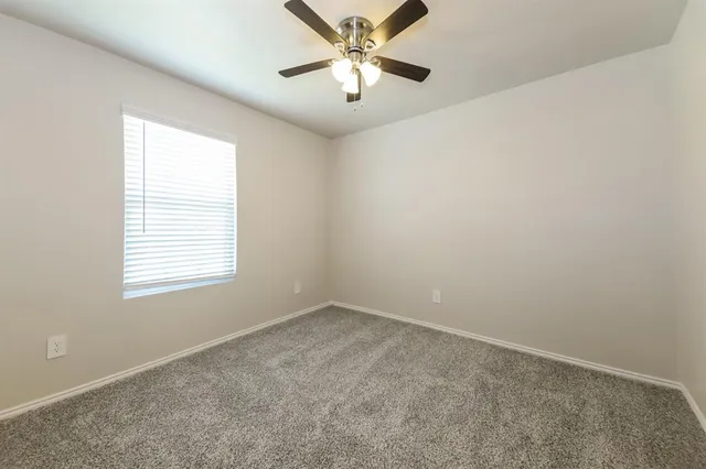 an empty room with a window and a fan