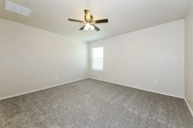 an empty room with a window and a fan