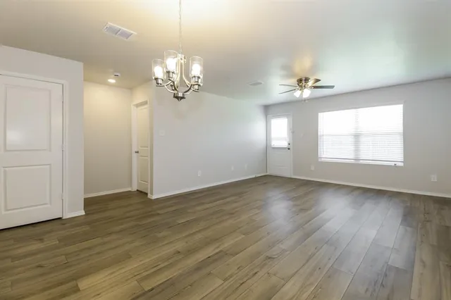 a view of an empty room with a window and wooden floor
