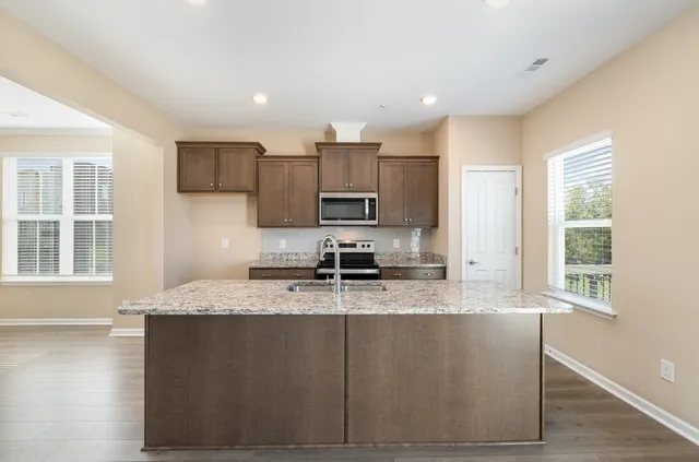 a large kitchen with granite countertop a sink a window and stainless steel appliances