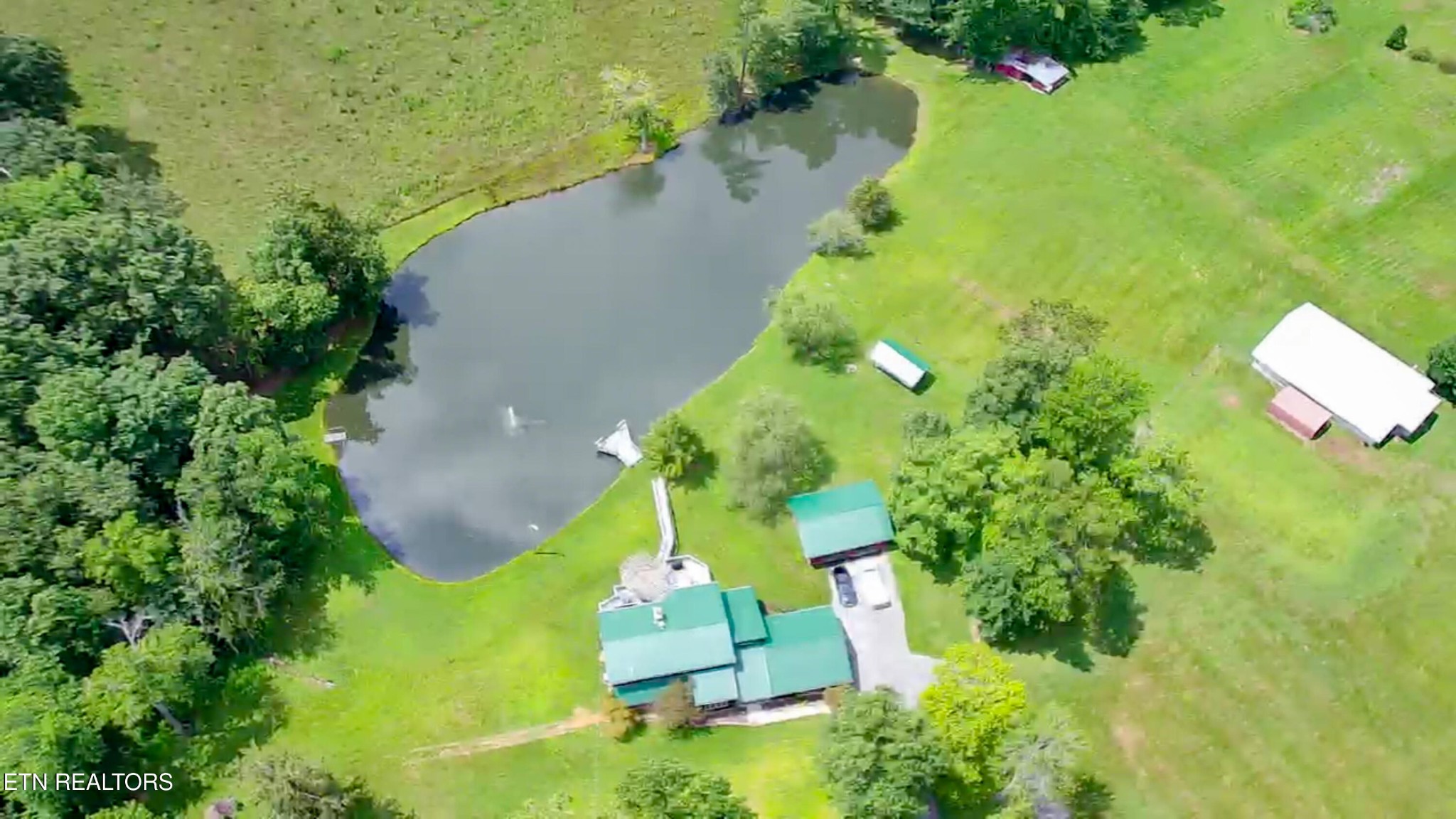 an aerial view of a house with a yard and trees all around