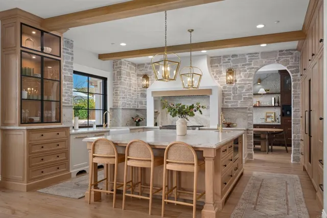 a large kitchen with kitchen island a large window and chairs
