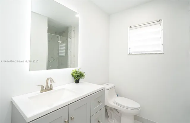 a bathroom with a sink vanity mirror and toilet