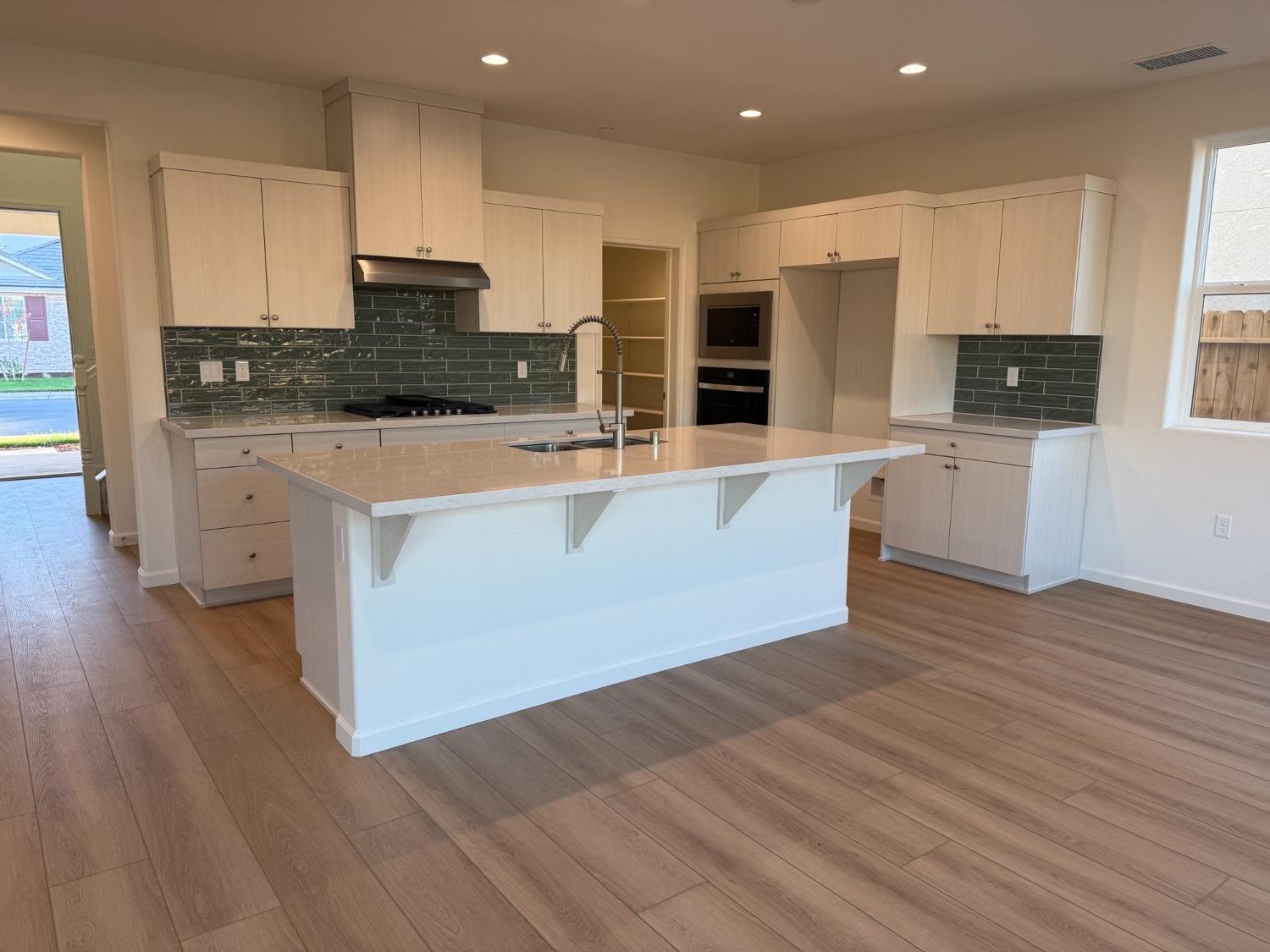 1268 Traverse Drive South Madera, CA 93636 - Photo 3 of 5 a large kitchen with stainless steel appliances wooden floors and wooden cabinets