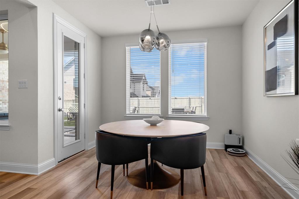 1308 Redbrick Lane Northlake, TX 76247 - Photo 17 of 40 a dining room with wooden floor a chandelier a wooden table and chairs