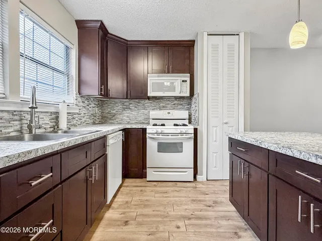 a kitchen with granite countertop stainless steel appliances a sink stove and cabinets