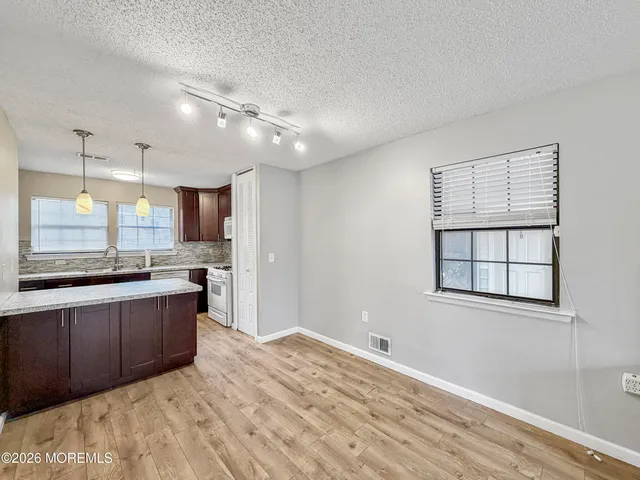 a view of kitchen and empty room with wooden floor