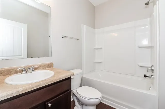 a bathroom with a granite countertop sink a toilet a mirror a bathtub and shower