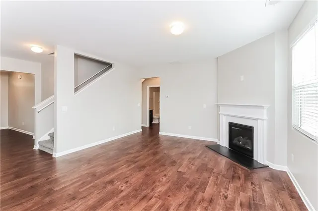 an empty room with wooden floor fireplace and windows