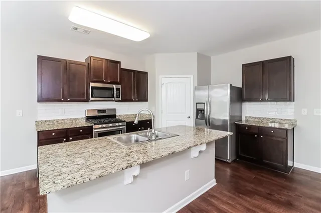 a kitchen with stainless steel appliances granite countertop a stove refrigerator sink and microwave
