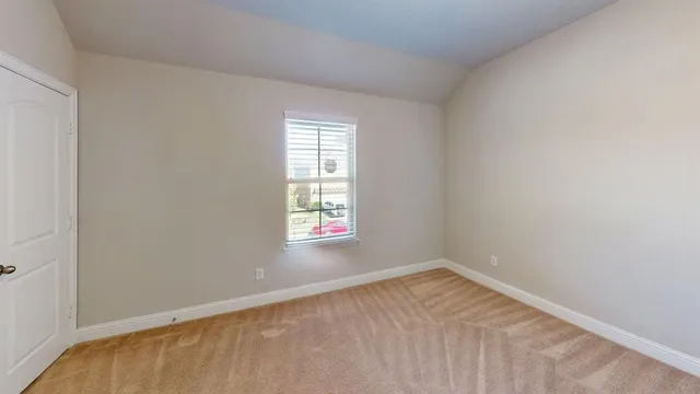 a view of an empty room with window and chandelier fan
