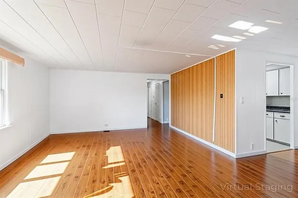 a view of a big room with wooden floor and windows
