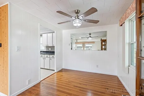a view of a kitchen with wooden floor a ceiling fan and windows