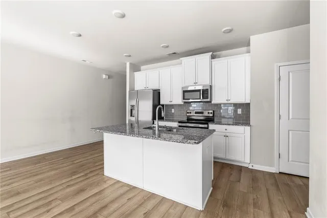 a kitchen with stainless steel appliances granite countertop a refrigerator a stove and a wooden floors