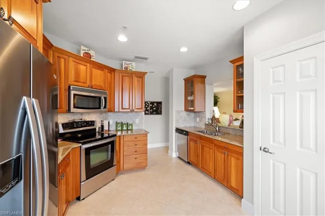 a kitchen with stainless steel appliances granite countertop a refrigerator stove top oven a sink and dishwasher