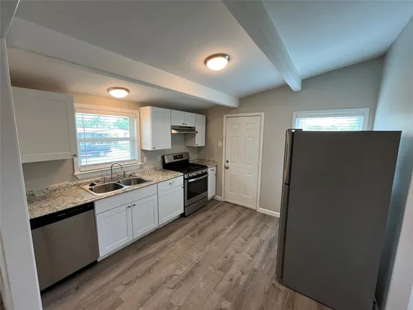 a kitchen with a sink a refrigerator a window and cabinets