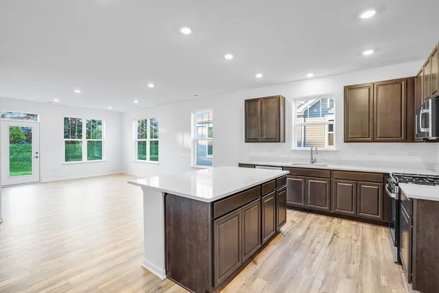 a large kitchen with stainless steel appliances granite countertop a large counter top a sink dishwasher and a stove with wooden floor