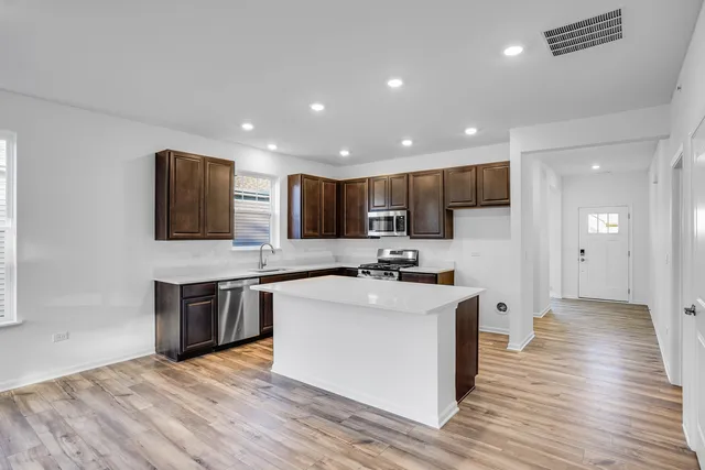 a kitchen with stainless steel appliances a sink stove and wooden floor