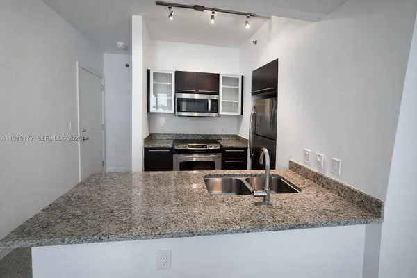 a kitchen with granite countertop a sink and stainless steel appliances