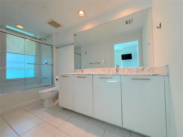 a bathroom with a granite countertop sink a toilet and mirror