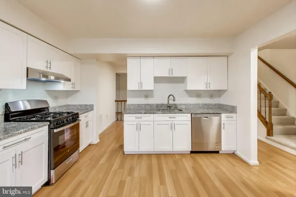 a kitchen with granite countertop wooden floors and stainless steel appliances