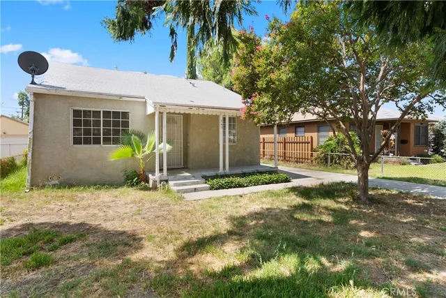 a view of a yard in front of a house with a large tree