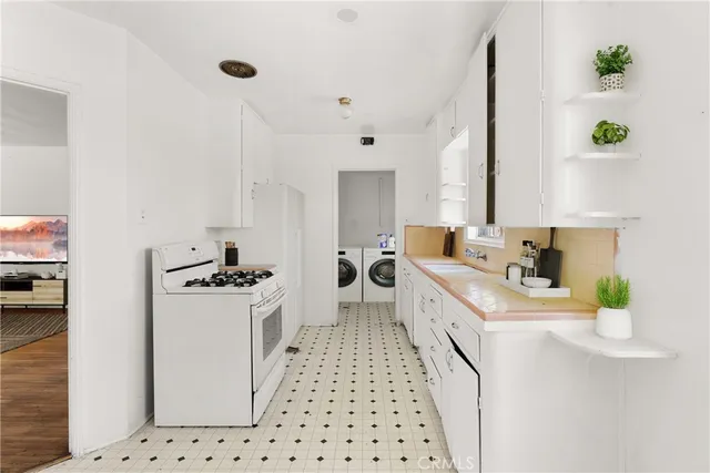 a kitchen with a sink a stove cabinets and white appliances